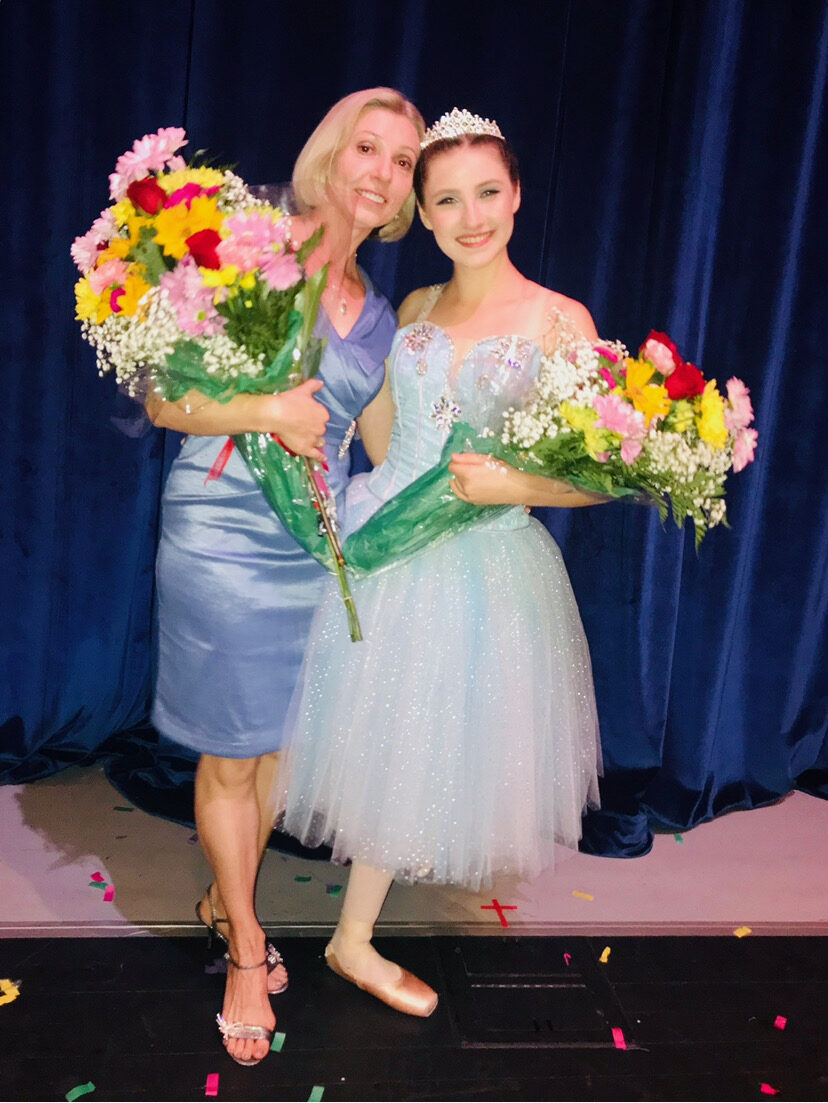 Brevard Ballet Academy director celebrating with a young dancer and bouquets after a Nutcracker performance