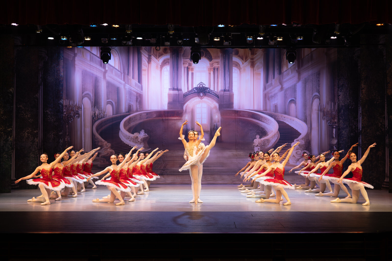 Corps de ballet in red tutus framing lead dancers during a Brevard Ballet Youth Company production